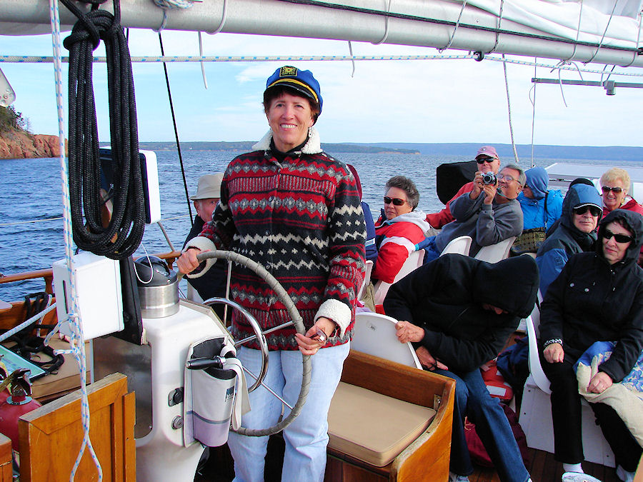 Eve DeLange Stearing The 'Amoeba' As We Sail The Bras D'or Lakes at Baddeck, Nova Scotia with Amoeba Sailing Tours. Travels, Tours, Photos, Pictures, Images, Information, & Reviews.